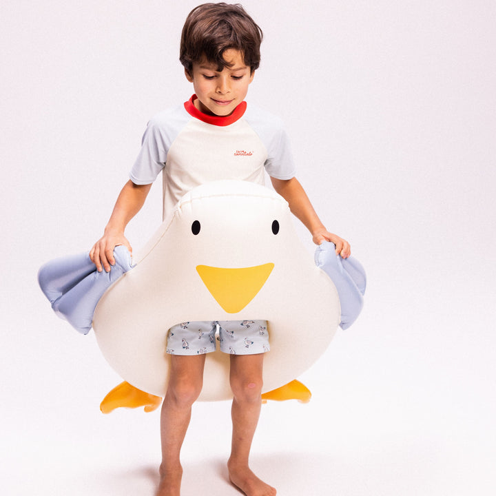 Child wearing a duck swim ringwith a plain background